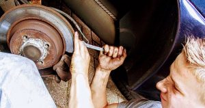 A young man using a wrench on a car's disc brakes in Wichita, KS