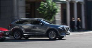 A silver 2019 Mazda MX-9 driving on a city street