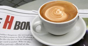 A cup of coffee resting on top of a newspaper