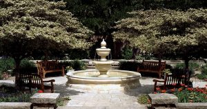 A beautiful marble fountain surrounded by benches and a garden at Botanica Gardens in Wichita, KS
