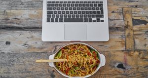 A bowl of pasta in front of an open laptop after being delivered in Wichita,KS