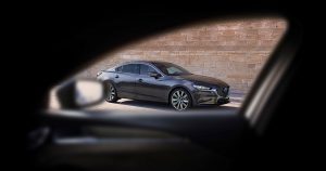 Looking through a passenger-side window at a gray 2019 Mazda6 parked on the street in Wichita, KS